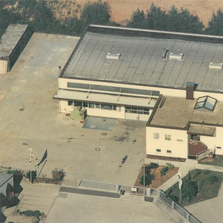 Alte Luftaufnahme der harich-Firmenzentrale in Sepia-Optik, Vogelperspektive zeigt Ursprungsgebäude vor Hallenanbau